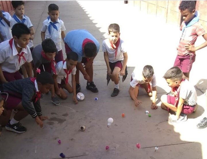 Alumnos de primaria jugando con los trompos creados por ellos.